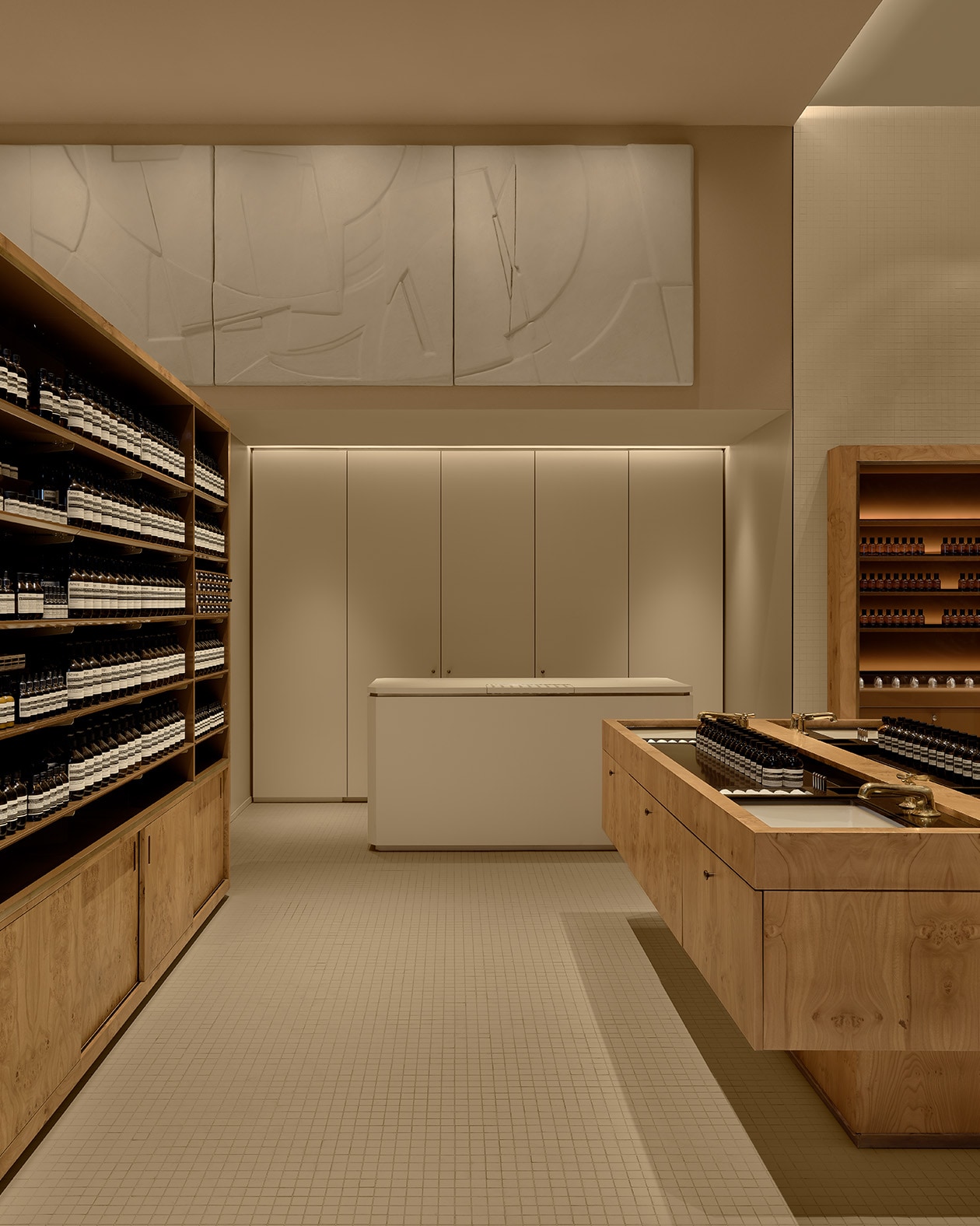sand colored store interior with product on wooden shelves on the left, a wooden basin unit on the right, and checkout counter centered ahead