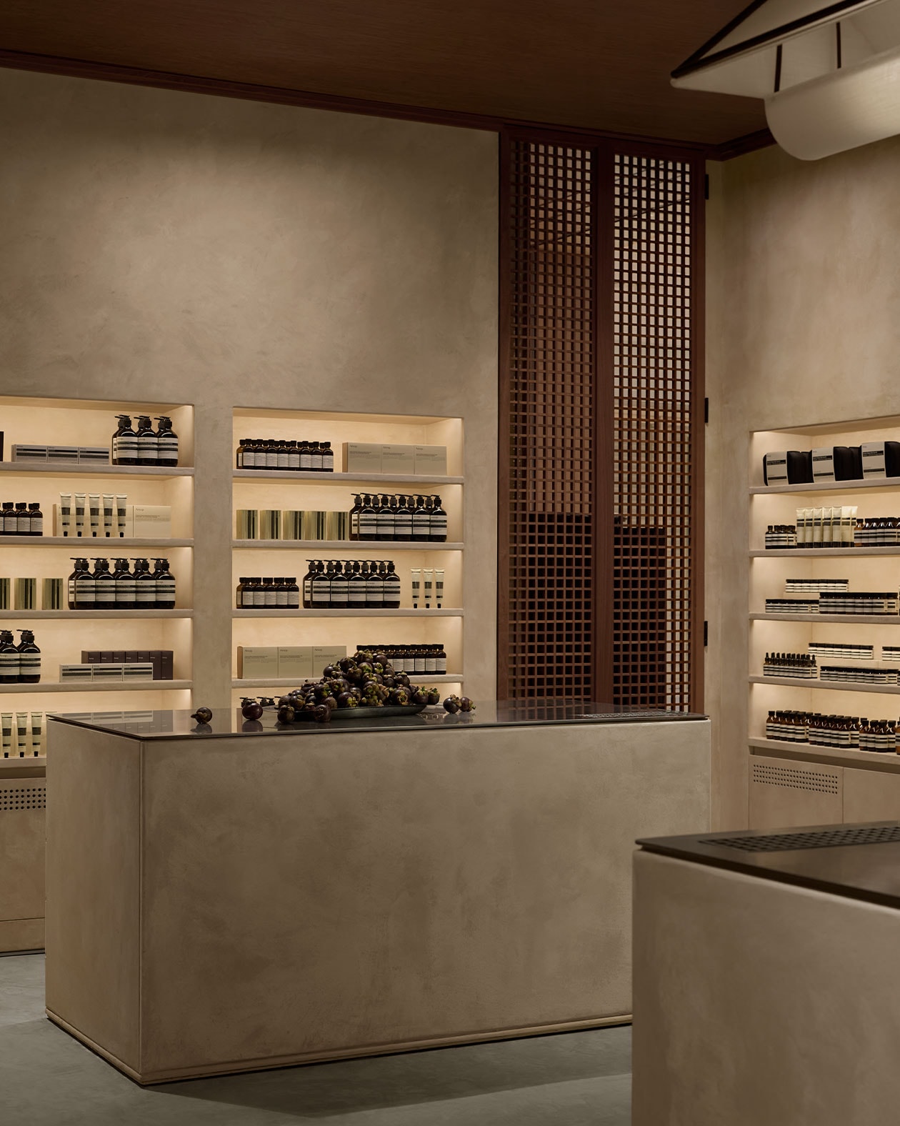 Aesop products are displayed on light-filled shelves, partially covered by wooden blinds that are “semi-open” depending on the angle of view.