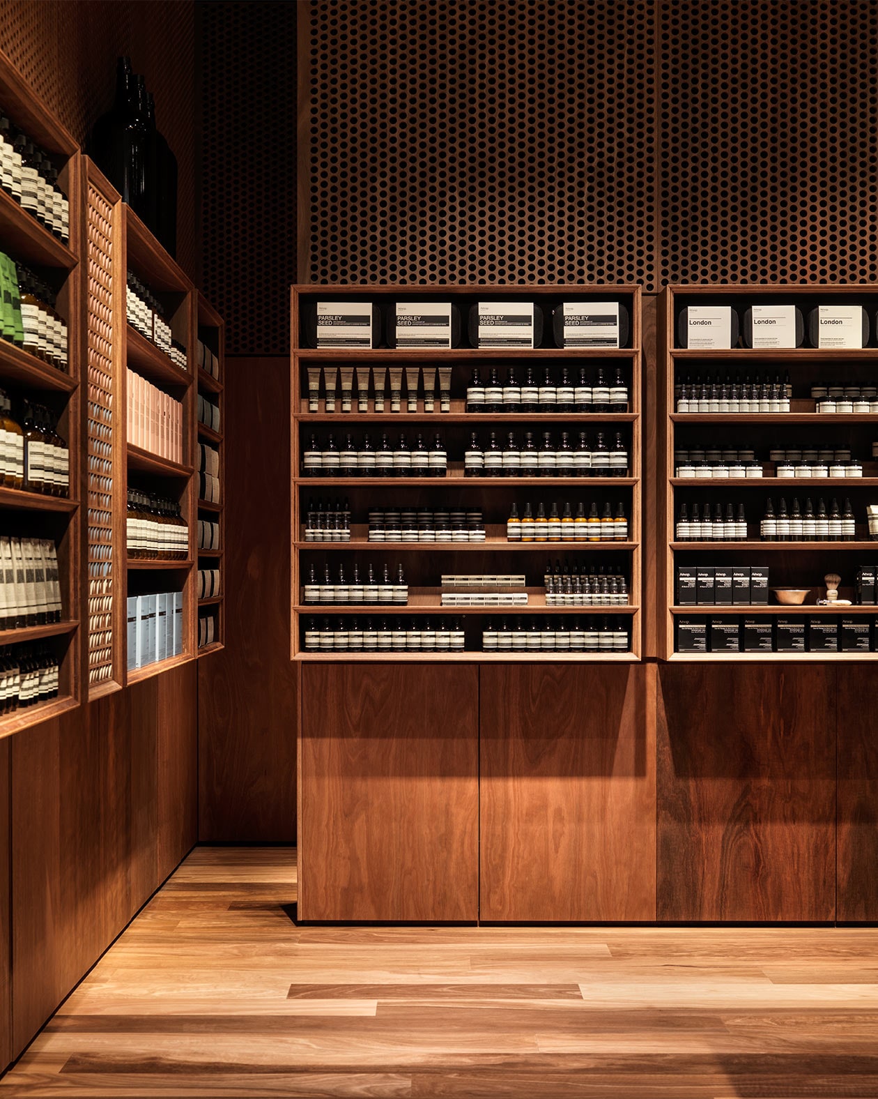 Dark timber shelving displaying several Aesop products.