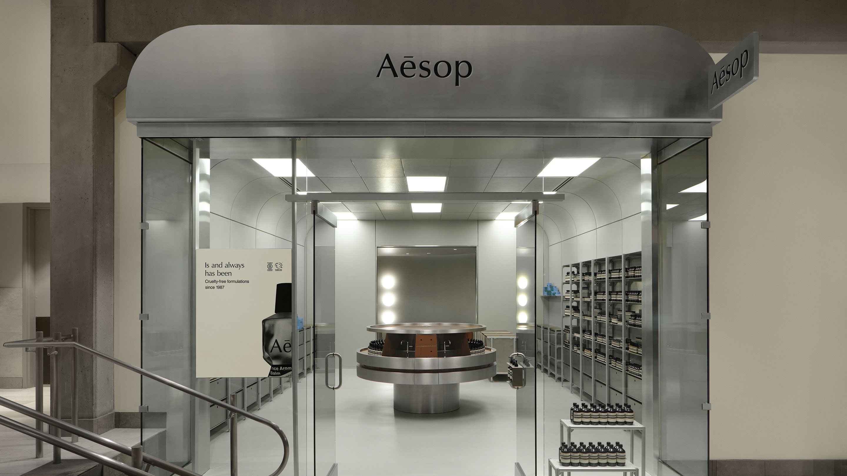 view of glass storefront looking into store, with stainless steel shelving and basins, with overhead fluorescent lighting