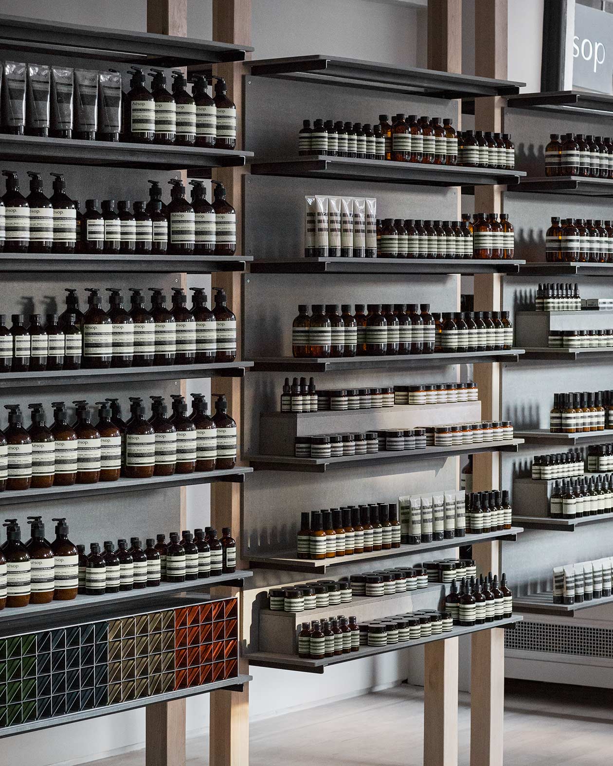 A close-up shot of steel shelving holding rows of Aesop skin care bottles.