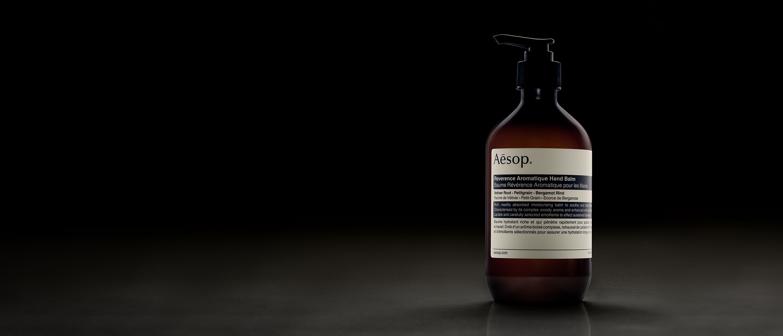 Reverence Aromatique Hand Balm bottle placed in front of dark background