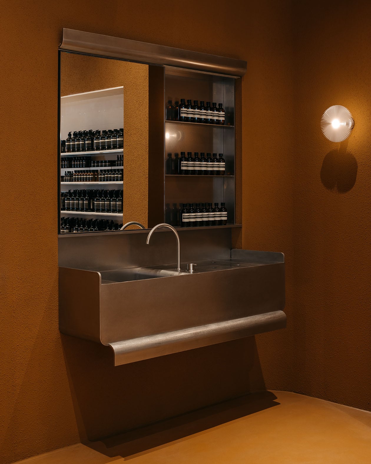 An individual basin in crisp stainless steel sit with a backdrop of rough and earthy stucco