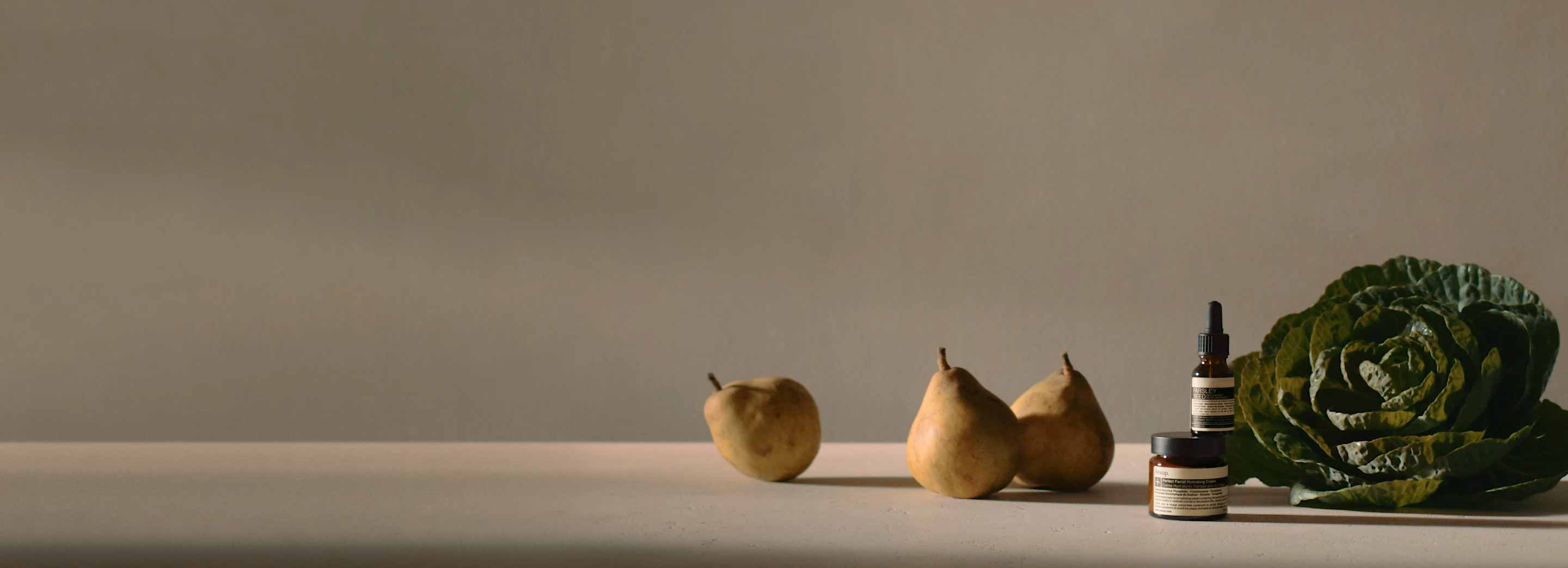 Two amber glass jars sitting next to a cabbage leaf and three pears.