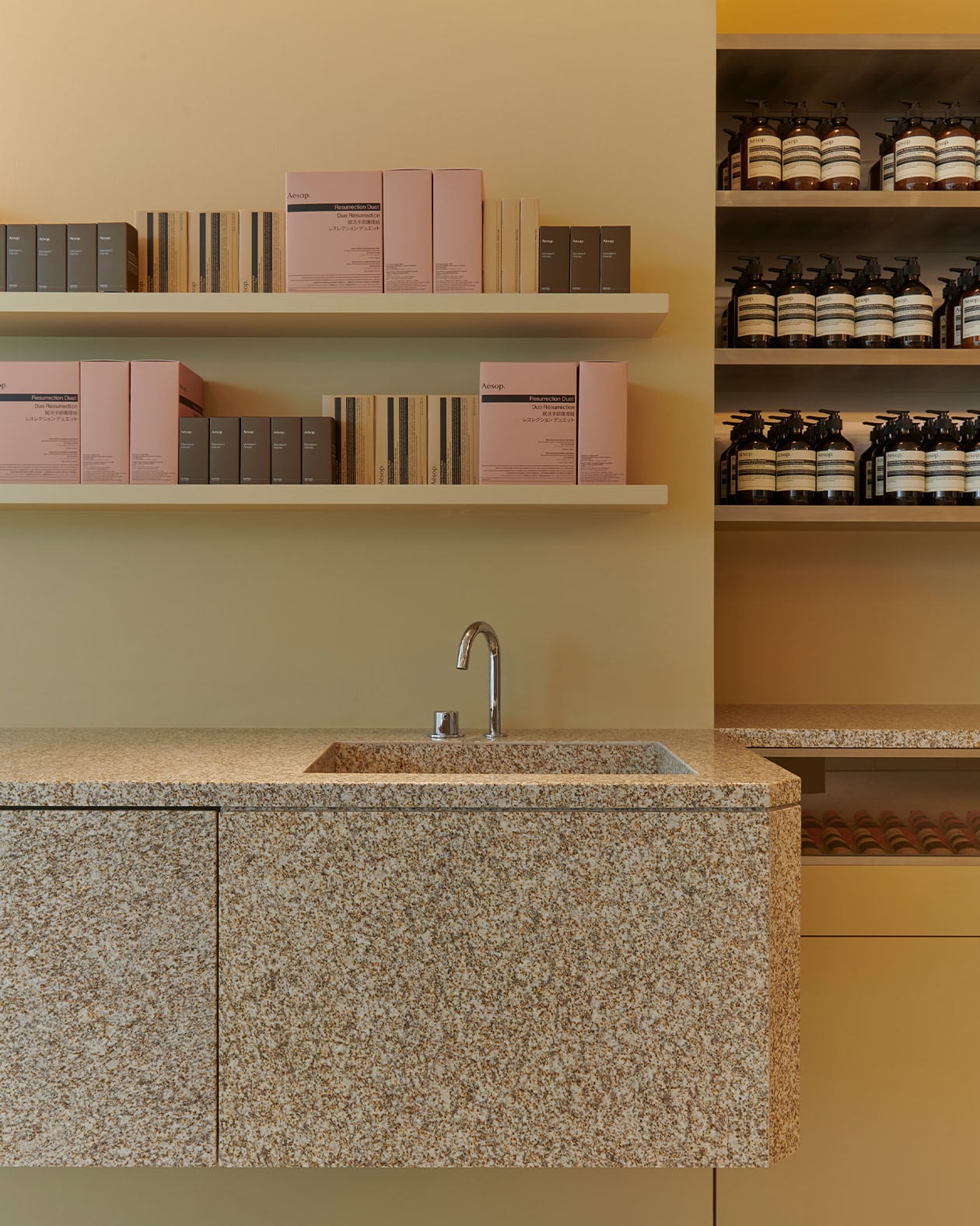 Flamed granite benchtops and floor tiles, Aesop products on the stainless-steel counter 