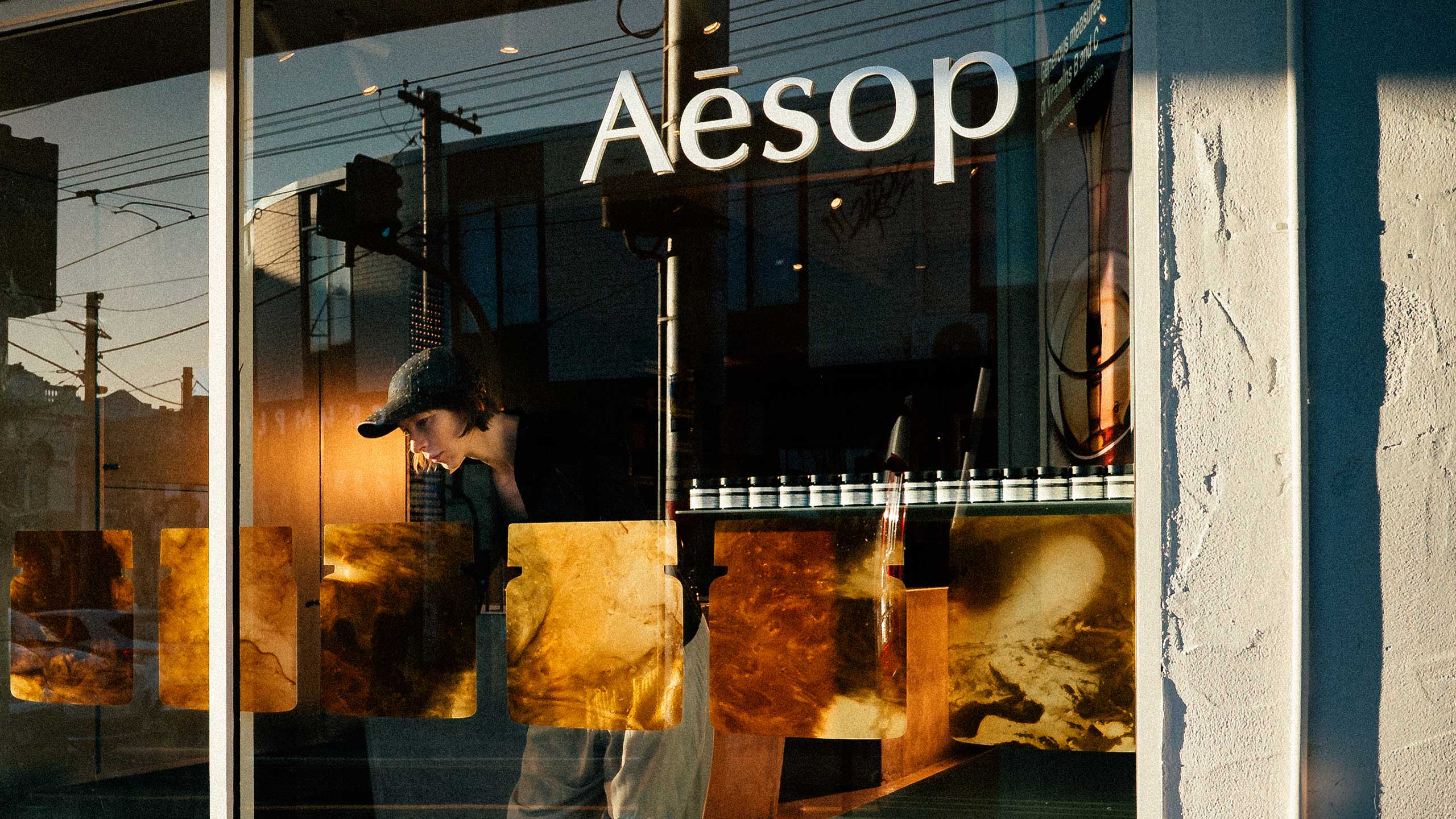 Jessie French placing her artwork on an Aesop store window.