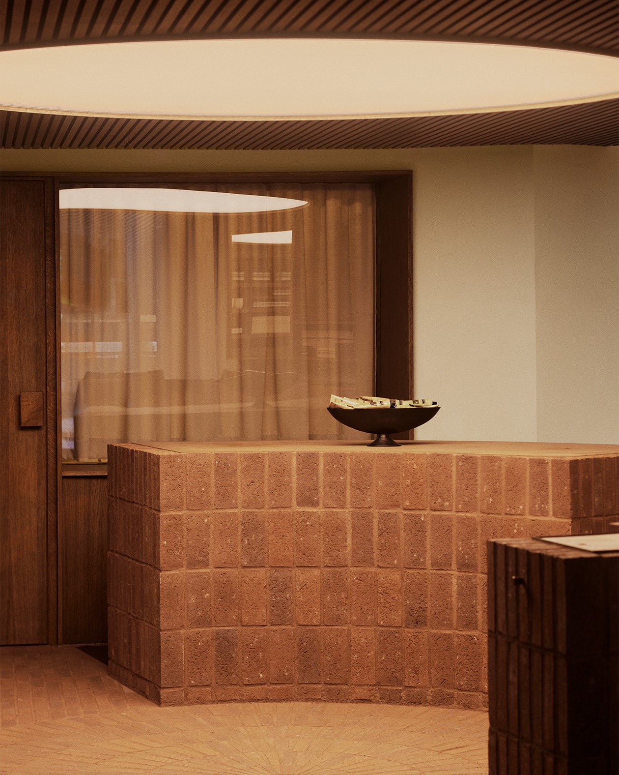 Aesop Kronprinsensgade store brick counter top, black serving bowl displaying hand balm products in metal tubes.