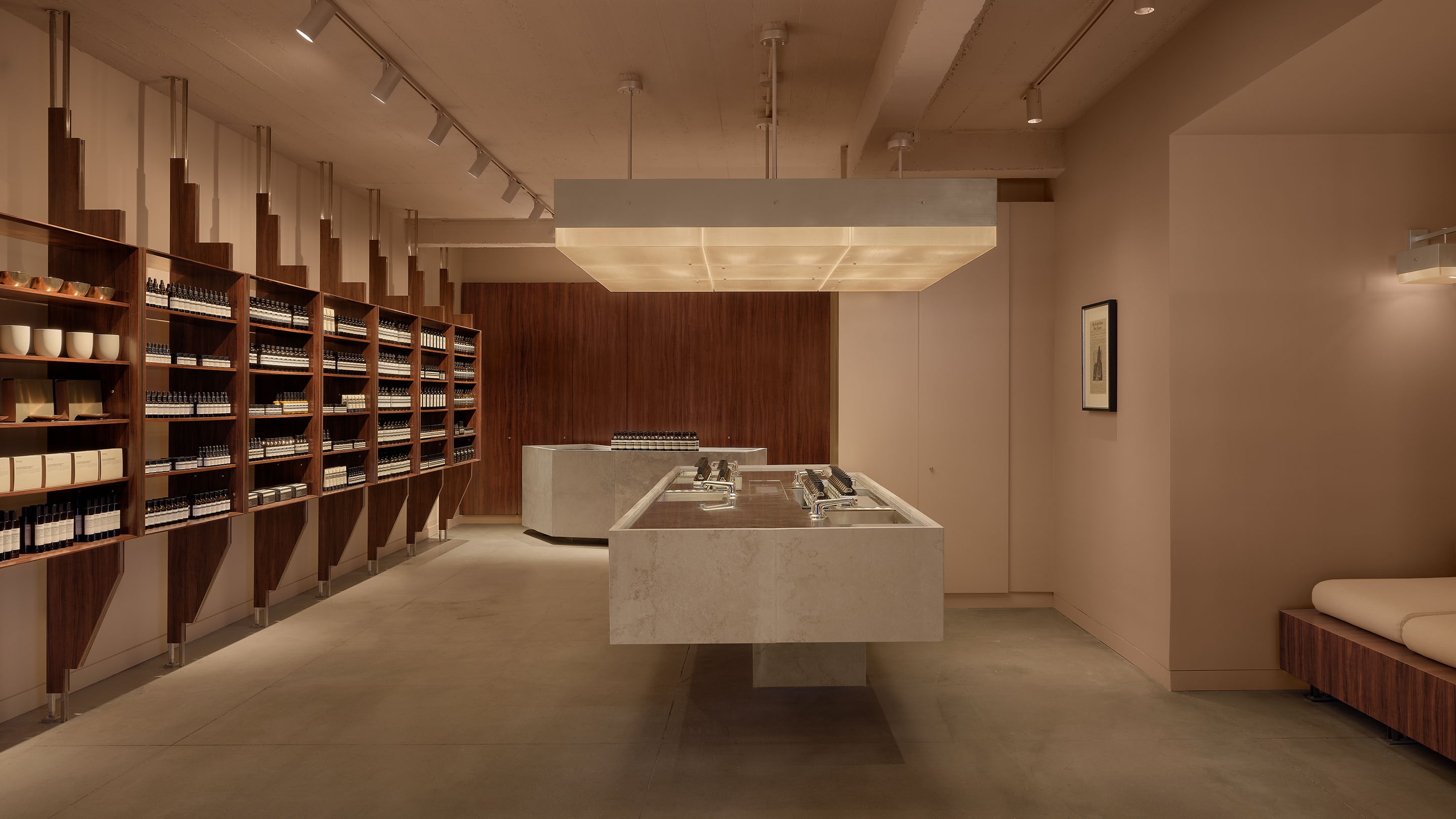store interior featuring large granite basin in the center of the room, a large overhead lamp above the basin, and product shelves lining the left wall