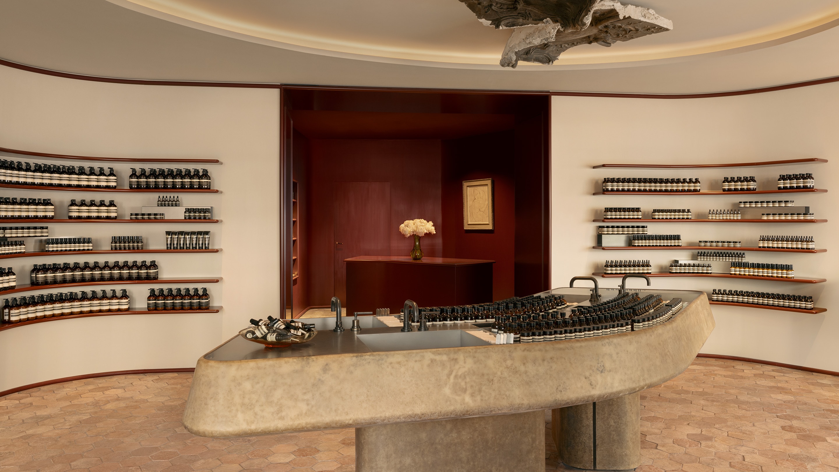 Aesop Avenue des Ternes store interior with stone basin and product displayed in neat rows across wooden shelving.