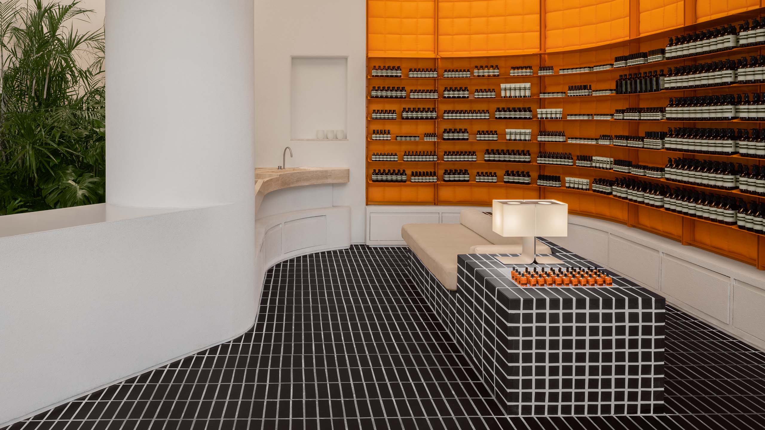 store interior featuring orange shelving product wall, padded chaise, and black tile floor with white grout