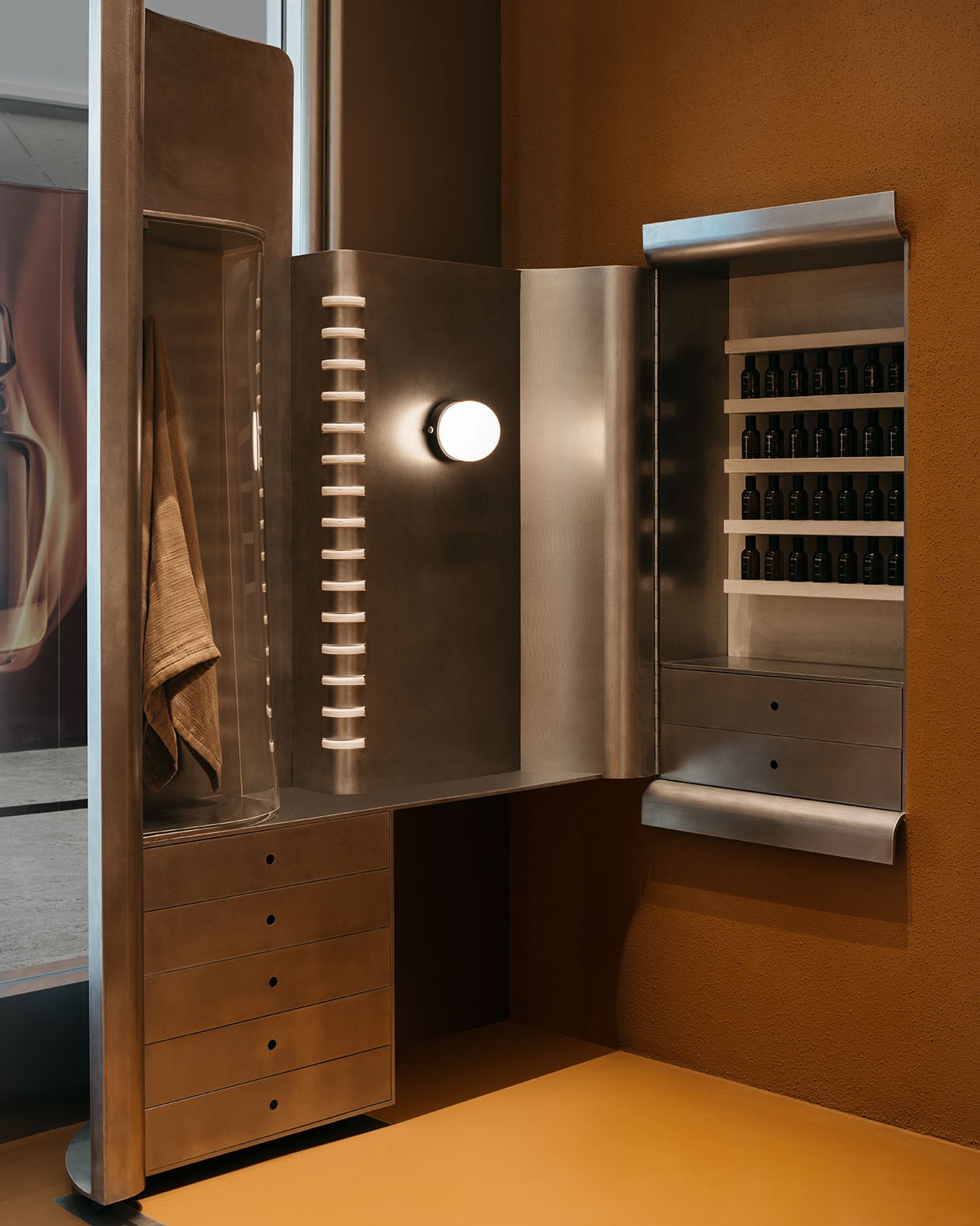 The polished metal tables as the reflective phone booths  are reimagined as a Fragrance Armoire.