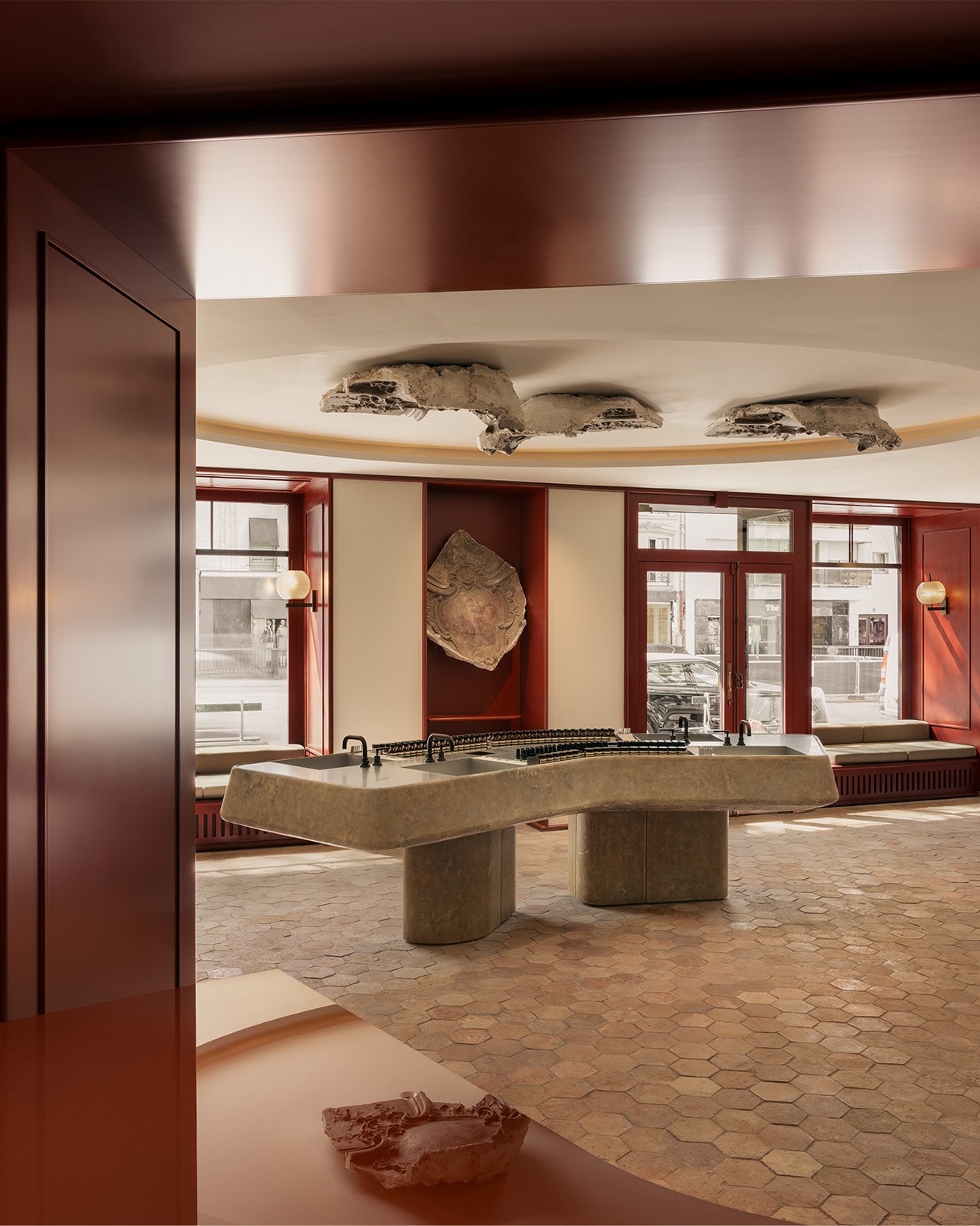 Aesop Avenue des Ternes store stone tiles and basin. Windows with integrated seating and stone sculptures placed around the room as well as mounted on the ceiling.