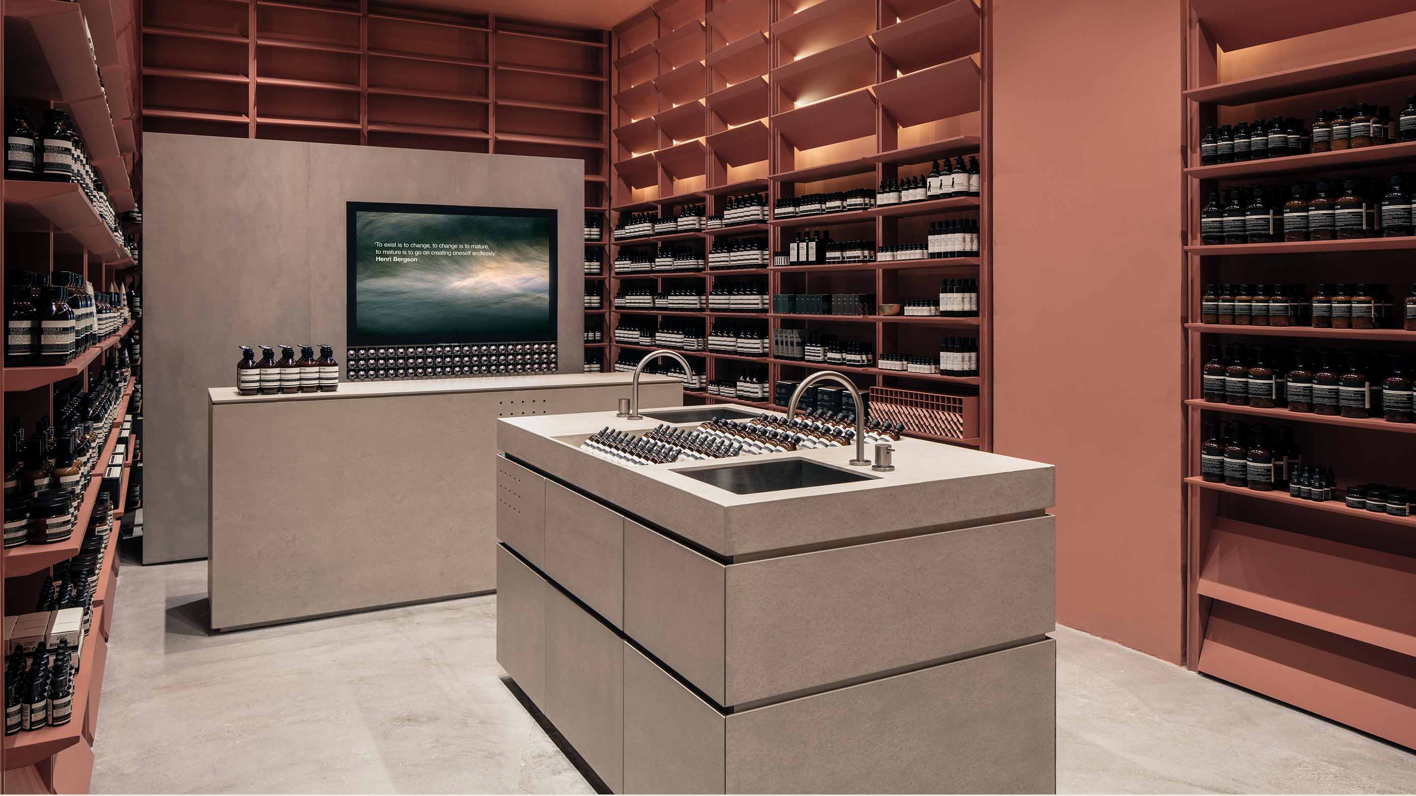 The interior of the store is crafted from brushed concrete floors and counters, surrounded by blush copper tones.